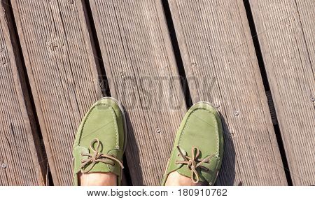 man feet in green top siders standing on wooden floor