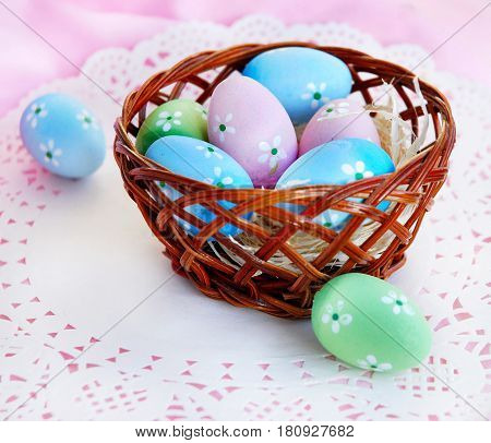 Easter still life with Easter eggs and wicker kartinoi on a pink background.