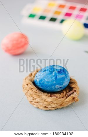 Deep Blue Easter Egg On Nest Over Bright Background.