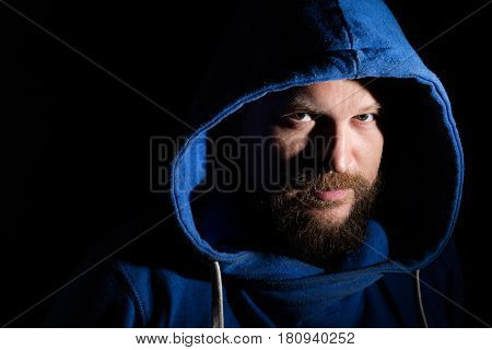 Solid bearded middle-aged man in a hood  portrait on black background