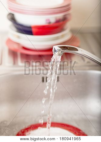 Cleaning dishware kitchen sink sponge washing dish. Close up of female hands in yellow protective rubber gloves washing