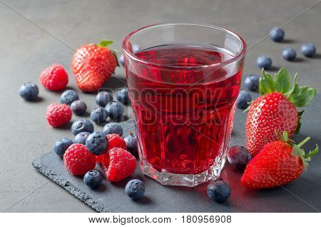Glass of fresh juice made of raspberries strawberries and blueberries on a slate plate