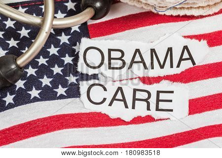 Obama Care on torn paper laying on an American flag with a stethoscope