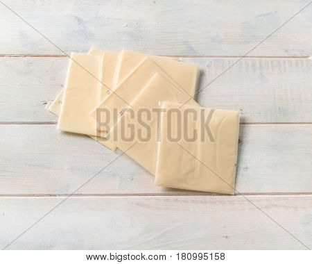Slices of yellow american cheddar wrapped in plastic on the table, topshot