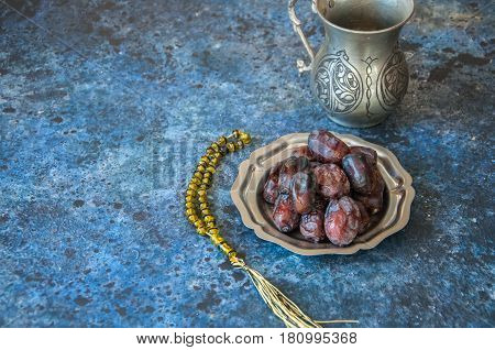 Dried Date Fruits Or Kurma Served On A Old Vintage Palte With Ornaments And Beads On A Blue Stone Ba