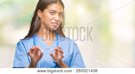 Young arab doctor surgeon woman over isolated background disgusted expression, displeased and fearful doing disgust face because aversion reaction. With hands raised. Annoying concept.