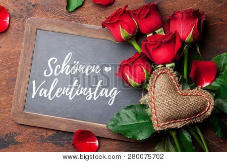 Valentine's day greeting card with red rose flowers bouquet on wooden background. SchÃ¶nen Valentinstag Germany. Top view with chalkboard for your greetings