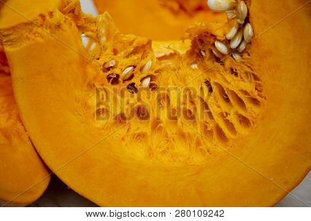 A Slice Of Tasty And Healthy Vegetable - Juicy Bright And Orange Pumpkin With Seeds On The Table Clo