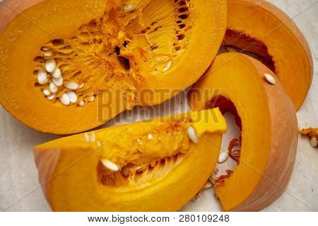 Juicy Bright And Ripe Pumpkin Cut Into Slices With Seeds On The Table. Pumpkin Oval-shaped Hard Crus