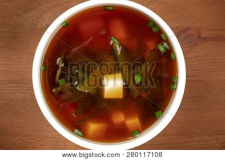 A Closeup Photo Of A Bowl Of Miso Shiru Soup With Tofu, Scallions, And Wakame Seaweed, Shot From The