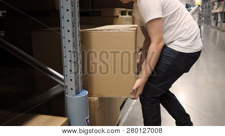 Warehouse Large Storage Or Logistic Or Cargo For Distribution. And Man's Hand Is Picking Up A Box.