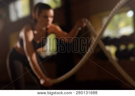 Fit, sporty and athletic sportswoman working in a gym. Womantraining using ropes. Sports, athletics, lifestyle and fitness.