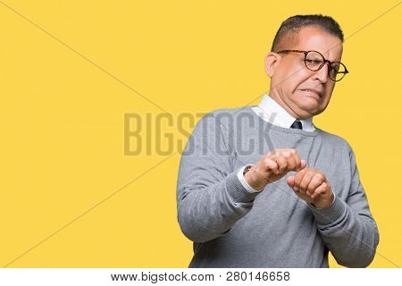 Middle age bussines arab man wearing glasses over isolated background disgusted expression, displeased and fearful doing disgust face because aversion reaction. With hands raised. Annoying concept.