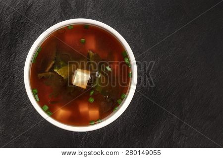A Photo Of A Bowl Of Miso Shiru Soup With Tofu, Scallions, And Wakame Seaweed, Shot From The Top On 