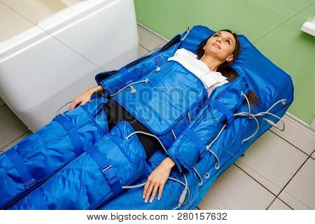 Woman In Pressotherapy Suit Lying Down Having Pressure Therapy For Weight Loss In Spa Salon