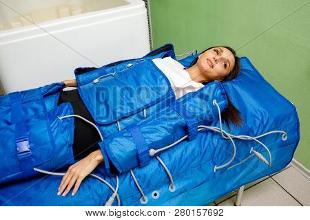 Smiling Woman Having Procedure Of Anti Cellulite Massage On Pressotherapy Machine In Beauty Center