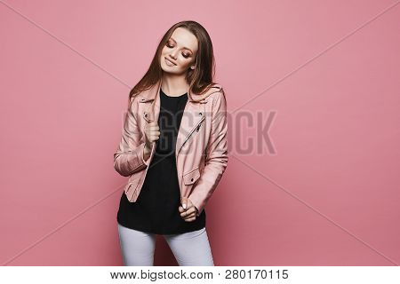 Charming And Sensual Blonde Model Girl With Bright Makeup In The Pink Leather Jacket And In Black Sa