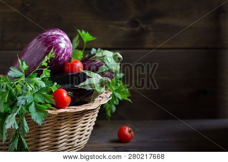 Ogranic Fresh Raw Purple Eggplant In A Wicker Basket On Wooden Background, Copy Space
