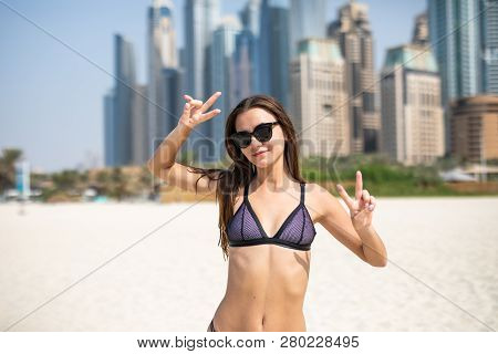 Portrait Of Young Woman In Bikini And Sunglasses Showing Peace Gesture On The Jbr Beach Standing In 