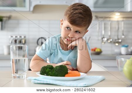 Unhappy Little Boy With Plate Of Vegetables At Table At Table