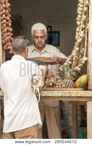 Trinidad, Cuba, Nov 27, 2017 - Store Keeper Specializing In Garlic Talks To Customer In Window