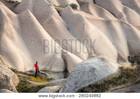 Amazing day in Cappadocia mountains, Turkey. Photographer in red jacket taking photo of amazing hills. Landscape photography