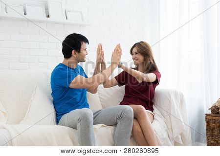 Close Up Of Attractive Pretty Young  Couple Clapping Hands Together While Sitting In Sofa At Home.
