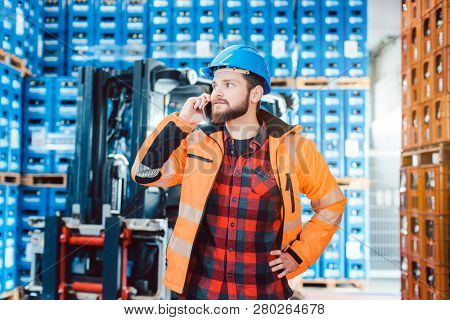Worker in logistics warehouse on the phone receiving instructions