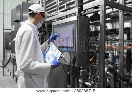 Technologist Taking Necessary Notes While Standing At Production Department Of Dairy Factory