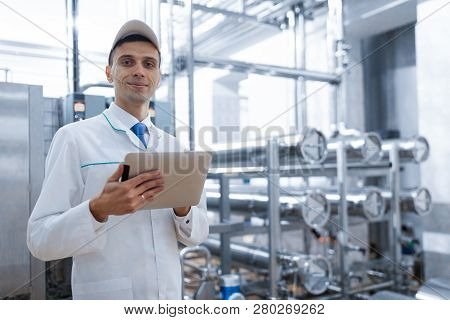 Technologist With A Tablet In His Hands At The Dairy Plant