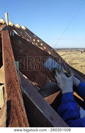 The Worker Screw The Screw Into A Screw Plate, A Roof Rack Of The Building Can Be Seen