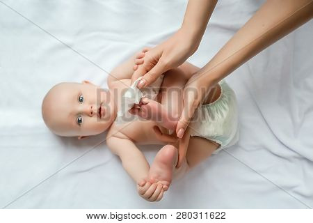 Newborn Baby Getting A Diaper Change: Mom Wiping Baby's Bottom With Baby Wipe. Emotions Of Newborn B