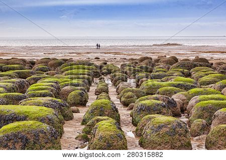 Distant Couple Walking On Hunstanton Beach, Norfolk, England, At Low Tide, In Winter.