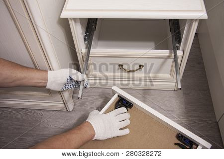 Repair And Installation Of Furniture In The Room. Male Workers Hands In White Gloves