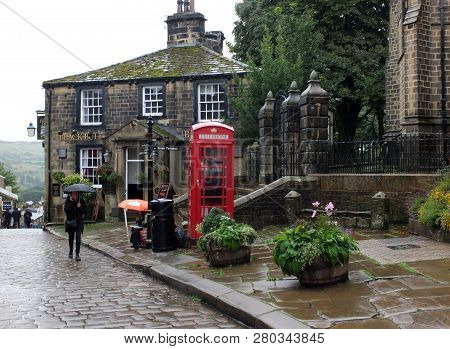 Howarth, West Yorkshire, England - 12 September 2018: Tourists Walking With Umbrellas On A Rainy Day