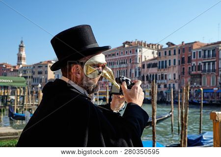 Venice, Italy - February 10, 2018: Man In A Pantalone Mask On The Peer Holding A Dslr Camera And Tak