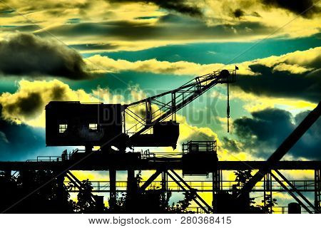 Siloutte Of An Old Ship Crane In Front Of Dramatic Overcolored Sky