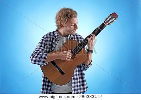 Young Man Playing Acoustic Guitar On Color Background