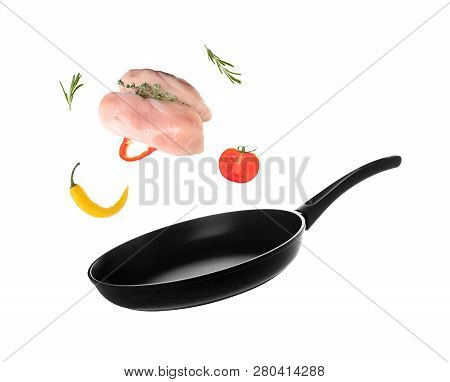 Nonstick Frying Pan With Falling Chicken Fillet And Vegetables On White Background. Delicious Recipe