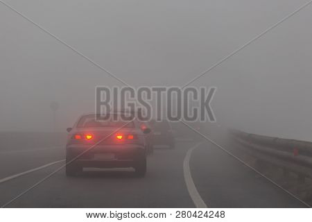 A Group Of Cars With Red Lights On The Road In The Fog