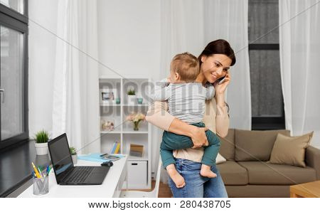 motherhood, multi-tasking, family and technology concept - happy mother with baby calling on smartphone at home