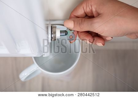 Person's Hand Turning Radiator Bleed Valve To Release Air