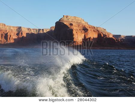Yolculuk tekne ile Lake Powell üzerinde seyahat. Pitoresk astern gemi dalgalar. Gün batımı ışınları aydınlatmak 