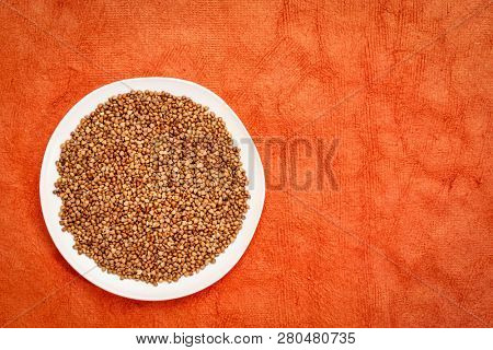 buckwheat kasha on a white plate against red textured background