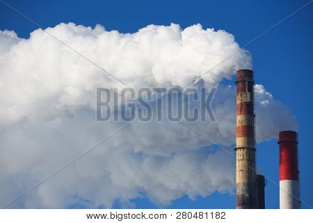 White Smoke Comes From Pipes Against Blue Sky. Problem Harmful Emissions And Air Pollution Of Centra