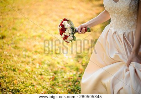 Bride In A White Wedding Dress Running With A Beauriful Red Roses Bouquet