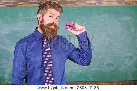 Man Bearded Teacher Or Educator In Formal Wear Holds Stapler Chalkboard Background. School Supplies 