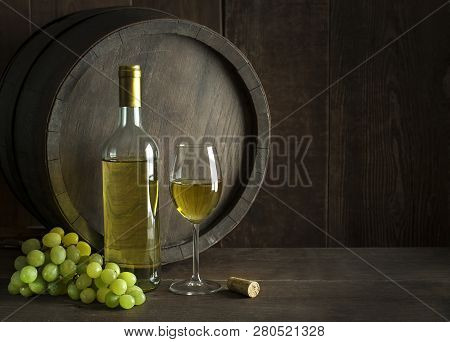Bottle Of White Wine With Cork. Glass Of Wine With Barrel Background