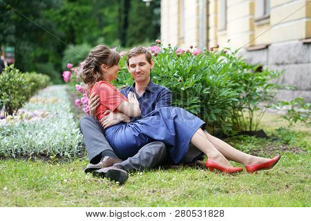 cute charming adult caucasian couple of lovers walking in the summer sunny park, kiss and hug with s