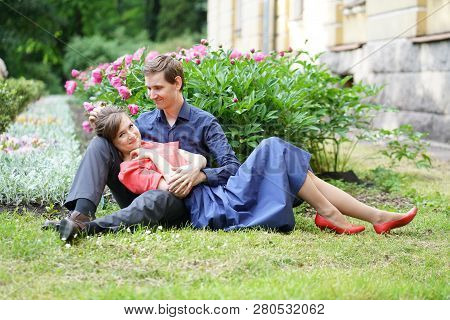 cute charming adult caucasian couple of lovers walking in the summer sunny park, kiss and hug with s